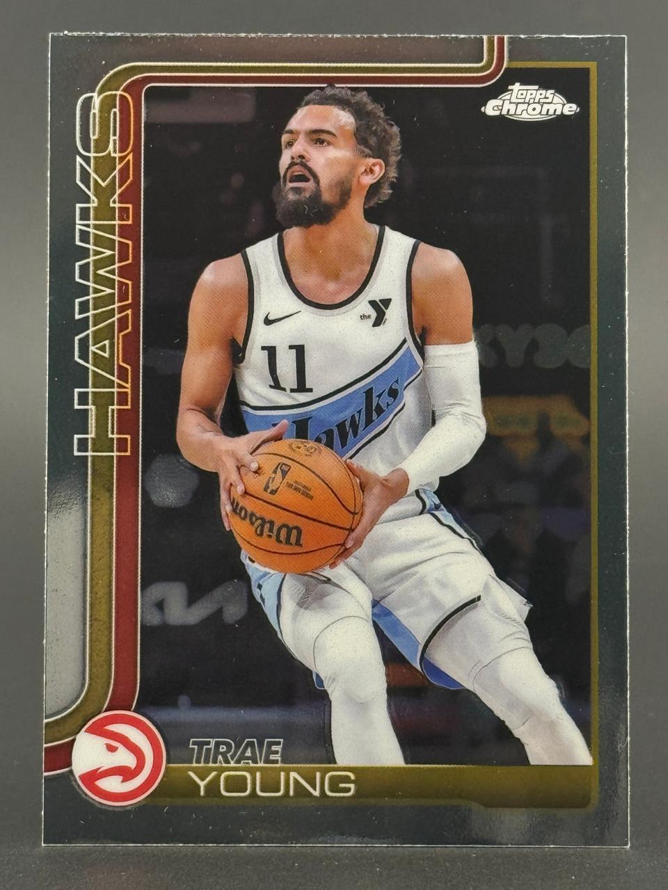 Trae Young holding a basketball on a Topps Chrome basketball card.