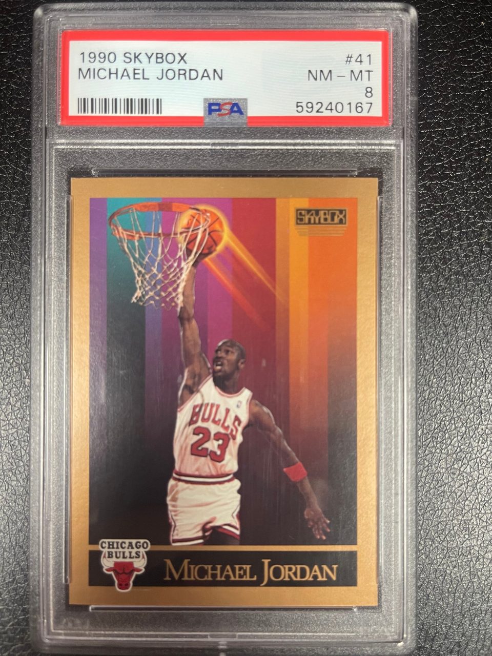 PSA 8 1990 SkyBox Michael Jordan #41 card dunking over a rainbow-striped background.