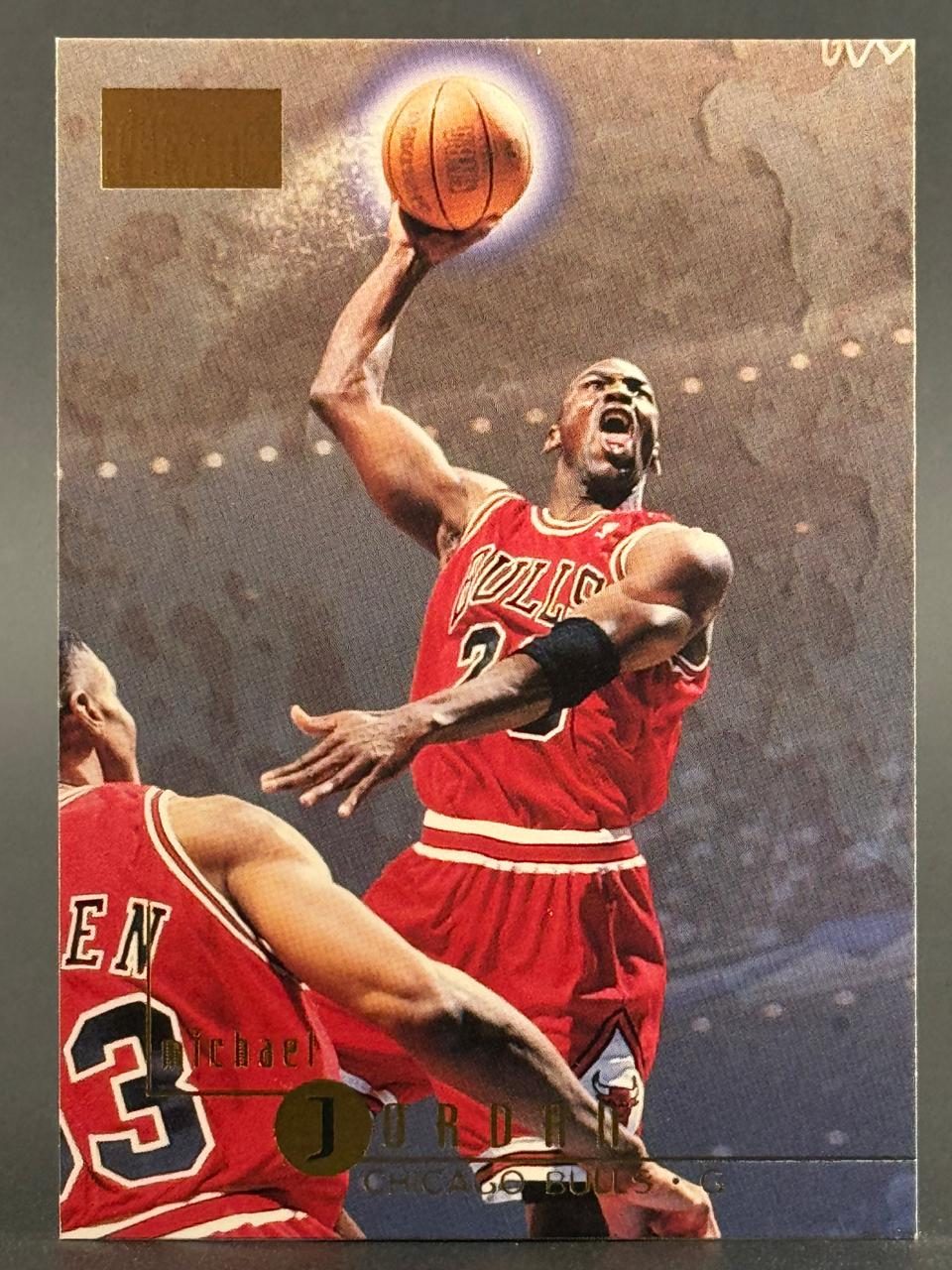Trading card of Michael Jordan in a Chicago Bulls uniform holding a basketball above his head.