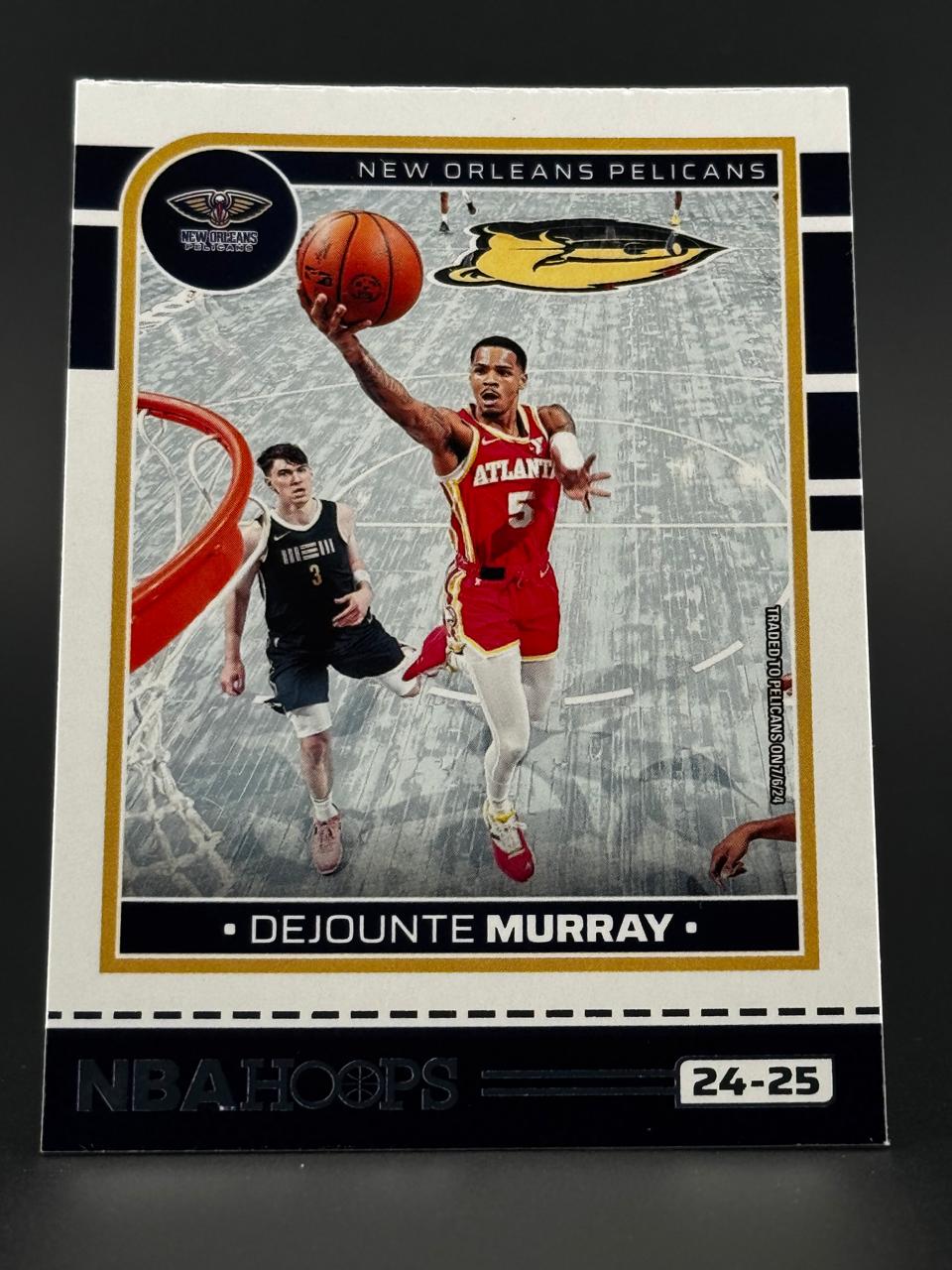 2024-25 NBA Hoops Dejounte Murray trading card featuring the New Orleans Pelicans in a white, black, and gold layout.