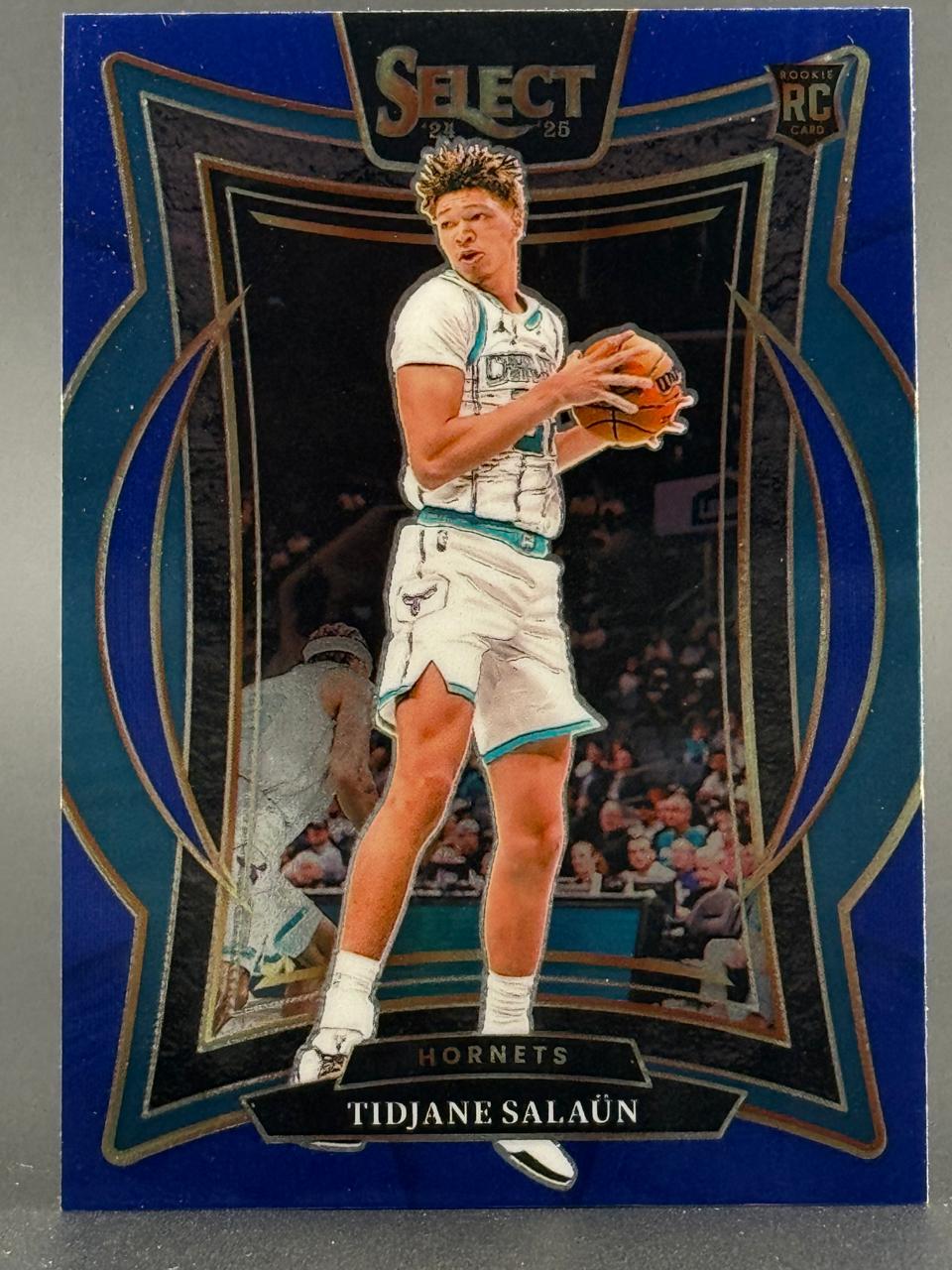 2024-25 Select Tidjane Salaün rookie card with a blue border, holding a basketball in uniform.