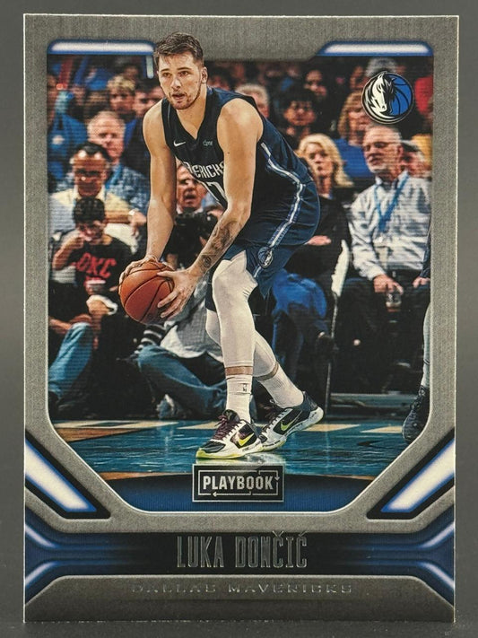 2021-22 Panini Playbook Luka Doncic basketball card holding ball with Dallas Mavericks.