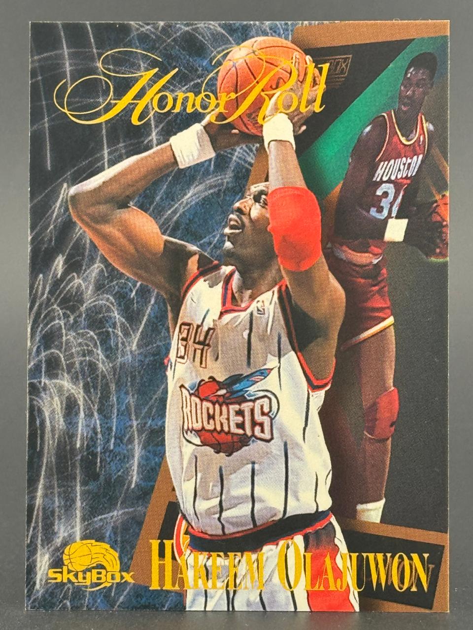 Hakeem Olajuwon SkyBox Honor Roll basketball card featuring two images of the player in Rockets uniforms.