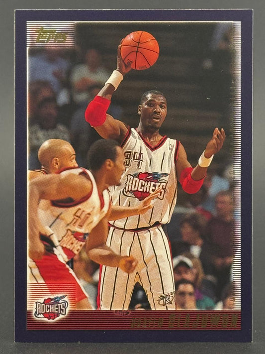 1994-95 Topps Hakeem Olajuwon basketball card #34, showing him holding a basketball in a Rockets uniform.