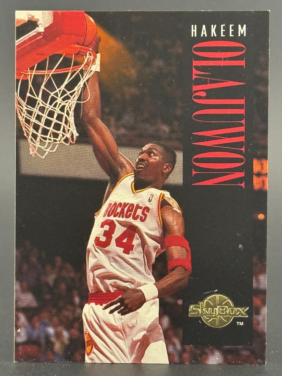Hakeem Olajuwon SkyBox basketball card featuring him dunking in a Rockets jersey.