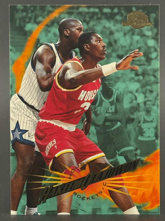Trading card featuring Hakeem Olajuwon in a red Rockets uniform, guarded by Shaquille O'Neal.