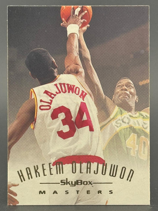 Hakeem Olajuwon SkyBox Masters basketball card showing him shooting over an opponent.
