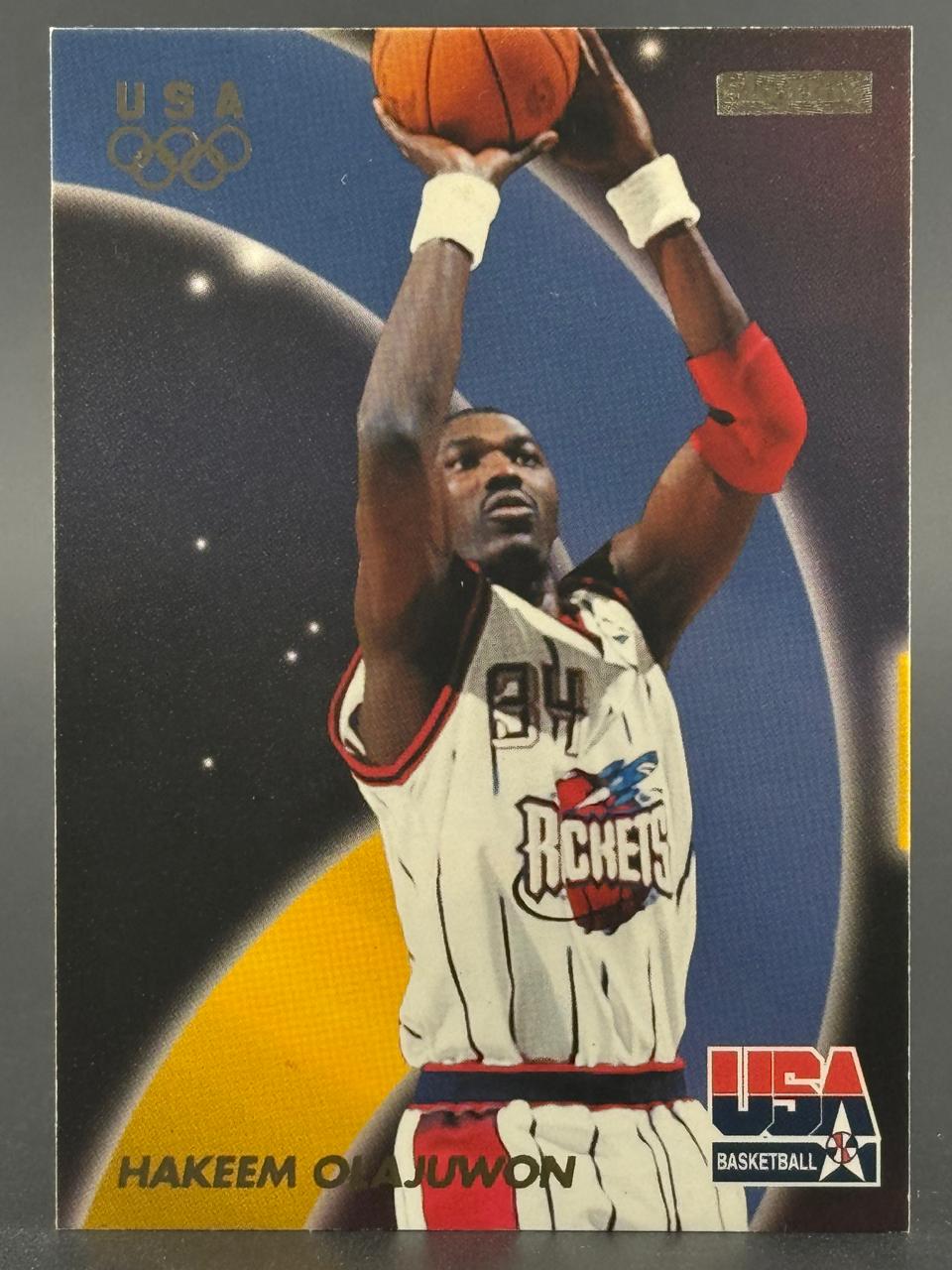 Hakeem Olajuwon basketball trading card, showing him in a Rockets uniform shooting a basketball.