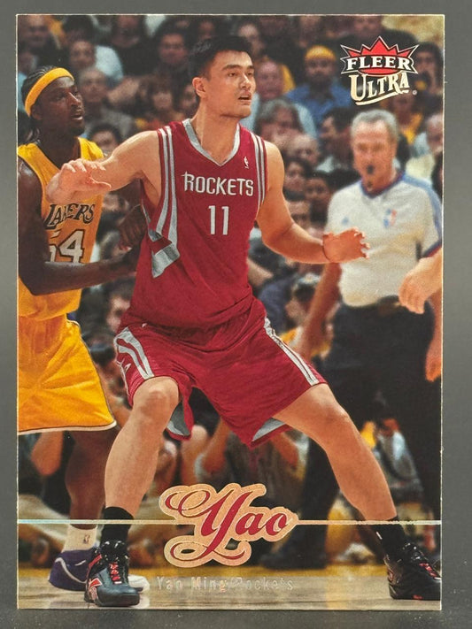2002-03 Fleer Ultra Yao Ming trading card featuring Yao Ming in his Rockets uniform guarding a Lakers player.