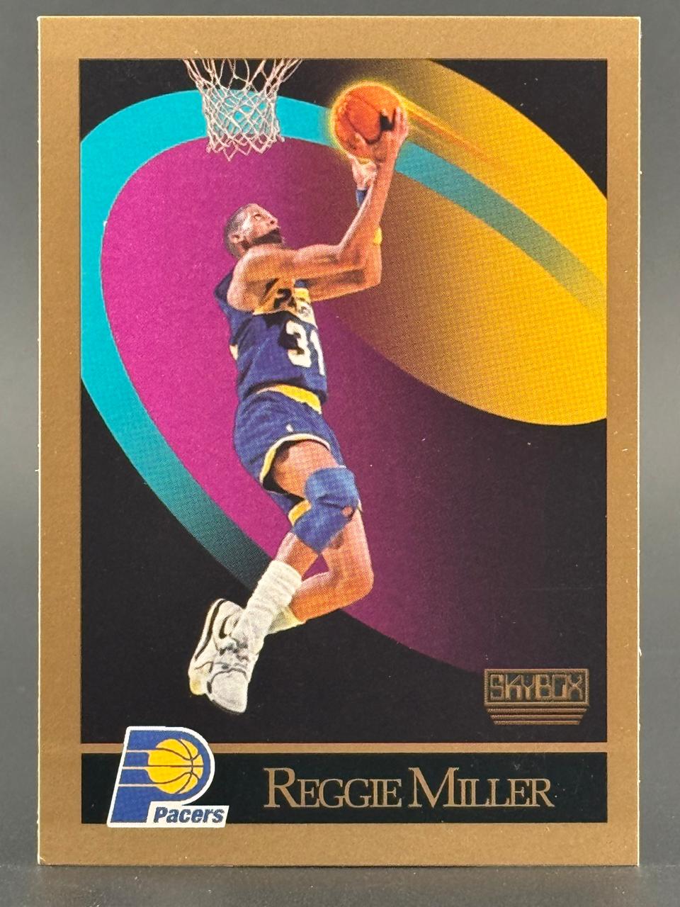 Reggie Miller 1990 SkyBox basketball card, featuring Miller shooting a layup against a colorful abstract background.