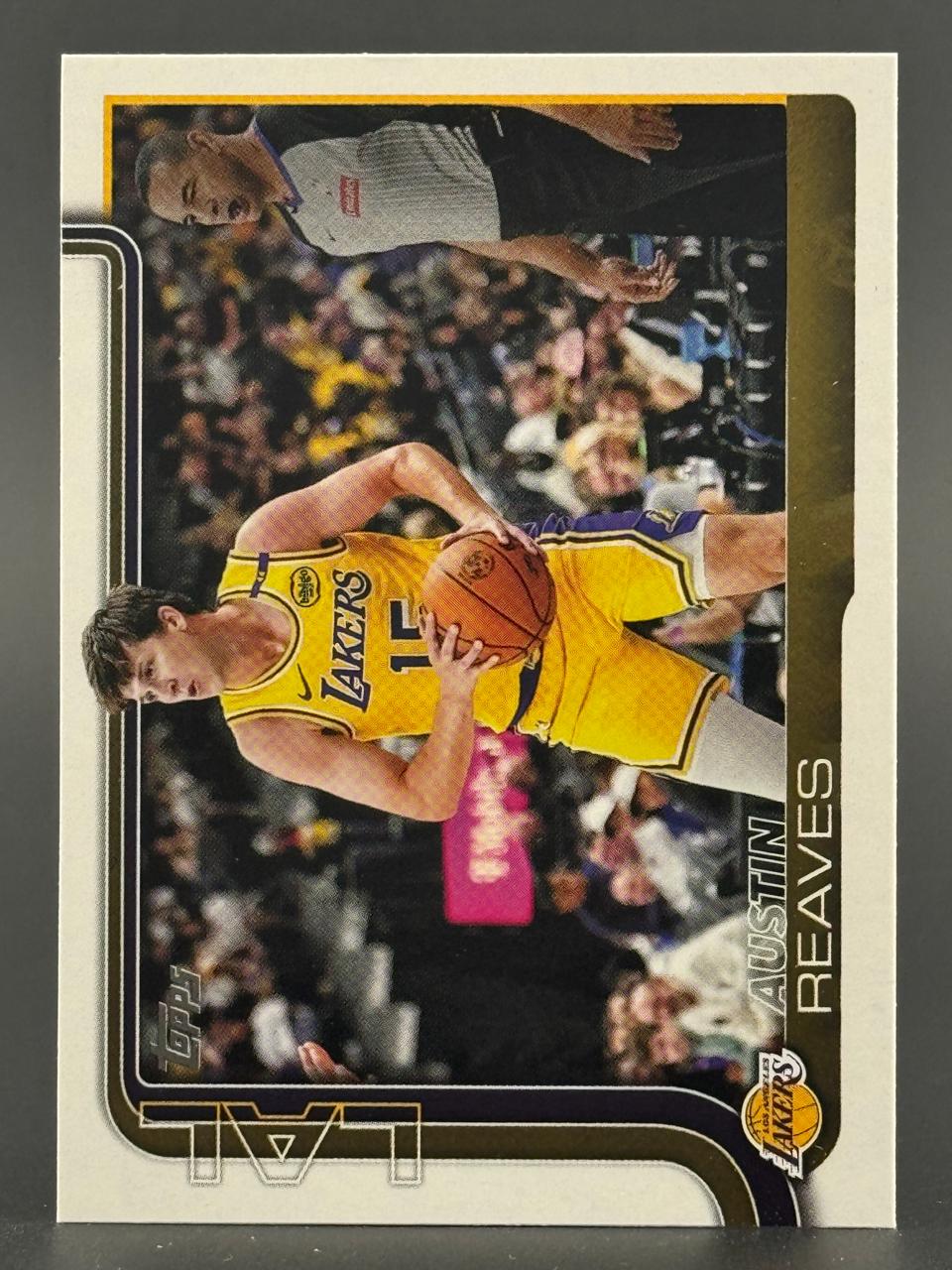 Austin Reaves trading card featuring him holding a basketball in a Lakers uniform.