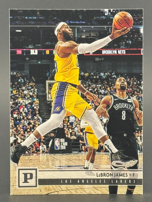 LeBron James trading card featuring him in a Lakers uniform driving to the basket past a Brooklyn Nets defender.