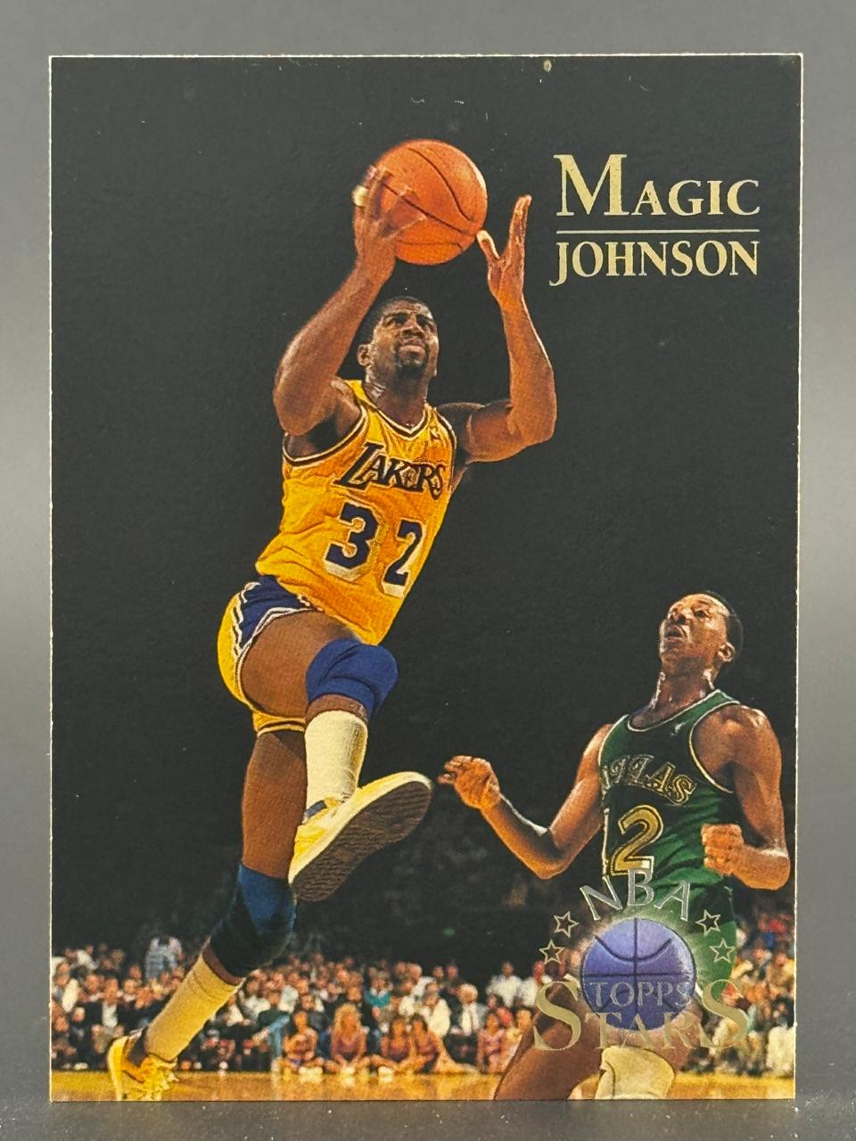 Magic Johnson basketball card showing him shooting while a defender watches.