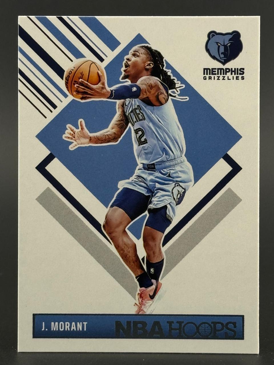 Ja Morant 2021-22 NBA Hoops basketball card, showing him in a blue Grizzlies uniform holding a basketball.