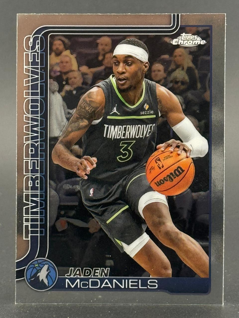 Jaden McDaniels basketball trading card dribbling a ball in a Timberwolves uniform.