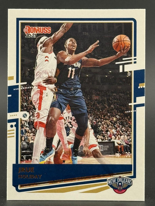 2020-21 Donruss Jrue Holiday basketball card featuring Holiday in a New Orleans Pelicans uniform driving past defenders.