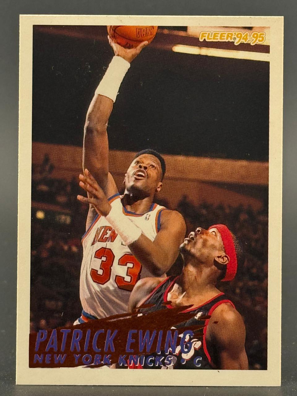 1994-95 Fleer Patrick Ewing trading card showing him shooting a basketball.