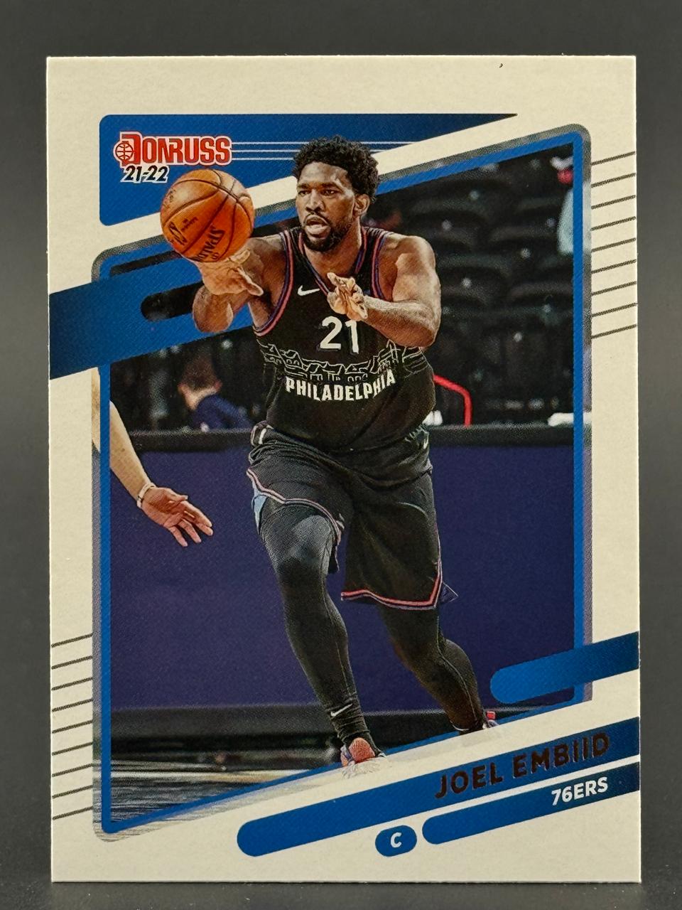 2021-22 Donruss Joel Embiid #21 basketball card featuring him passing the ball in a 76ers uniform.