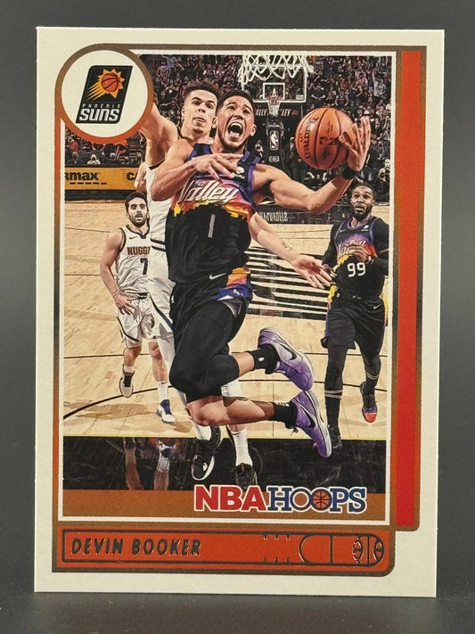 Devin Booker 2020-21 NBA Hoops trading card featuring Booker driving the lane in a Phoenix Suns uniform.