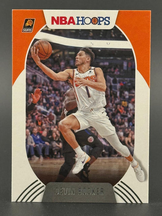 Devin Booker 2020-21 NBA Hoops trading card, showing him driving to the basket in a white Suns uniform.