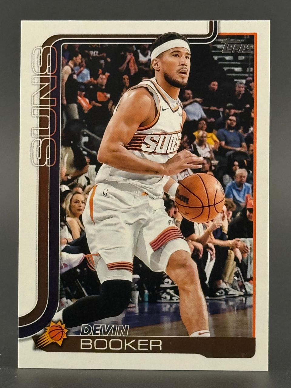 2024-25 Topps basketball trading card featuring Devin Booker dribbling in a Phoenix Suns uniform.