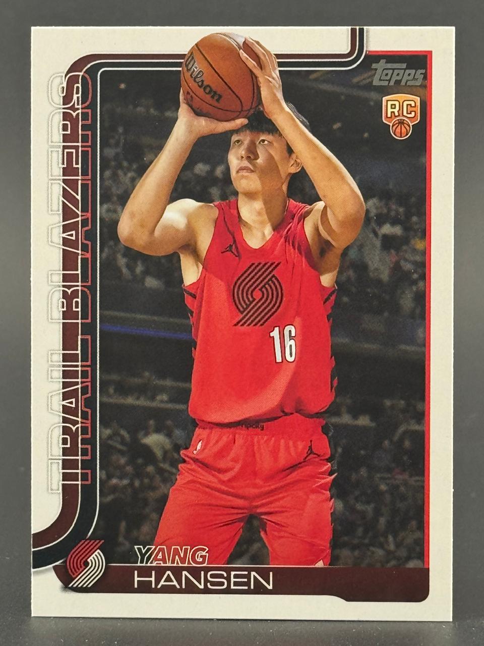 Yang Hansen basketball trading card showing him in a red Trail Blazers uniform holding a basketball.