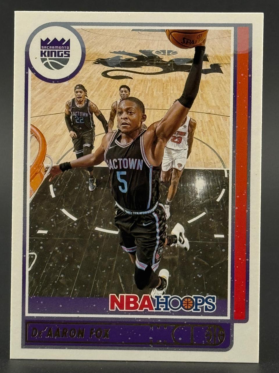 De'Aaron Fox 2021-22 NBA Hoops basketball card featuring Fox dunking in a Sacramento Kings uniform.