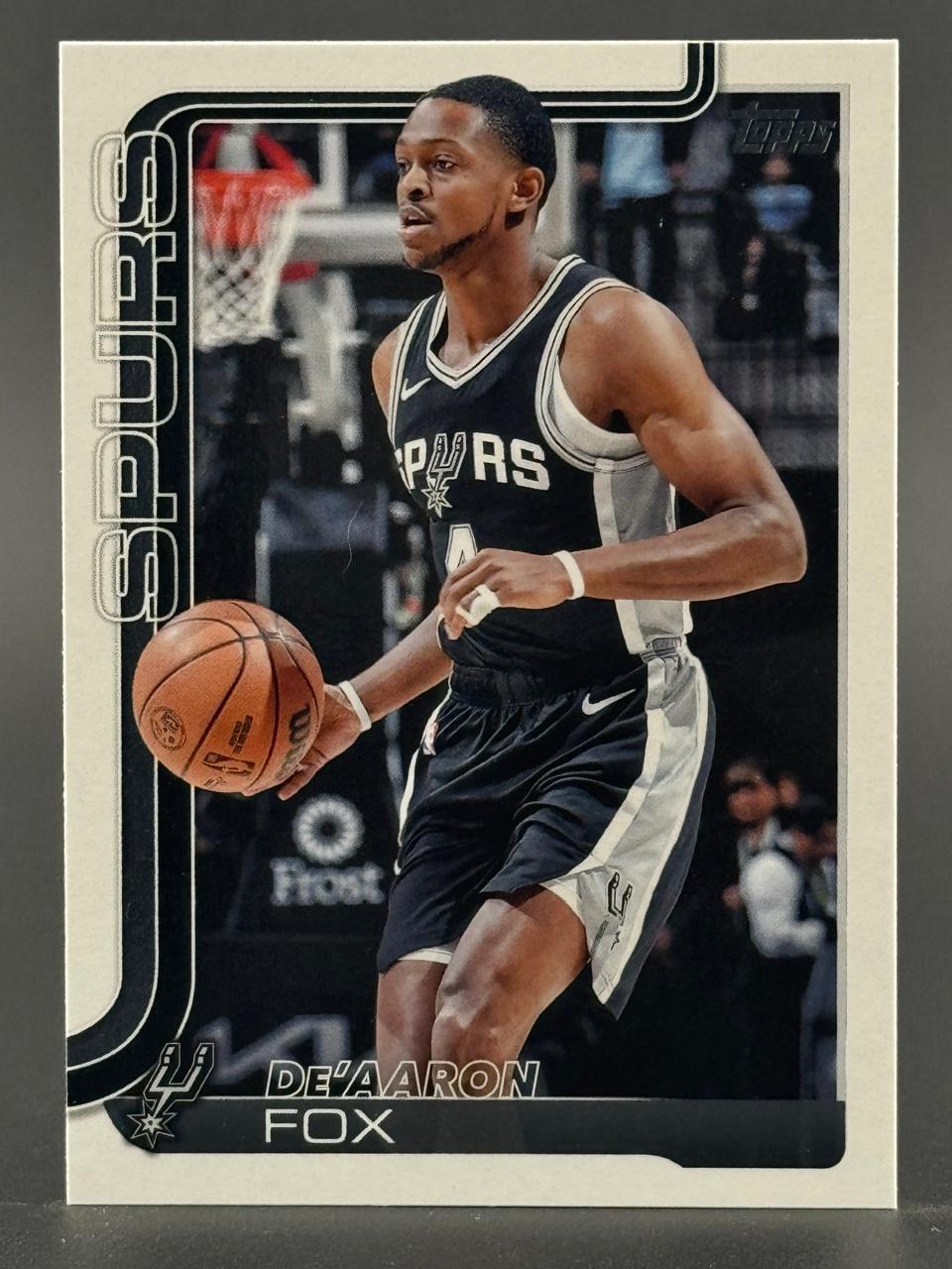 Trading card of De'Aaron Fox in a Spurs uniform dribbling a basketball.