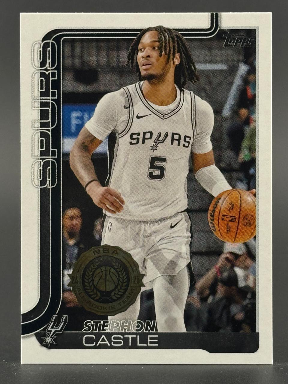 Stephon Castle basketball trading card featuring him in a white Spurs uniform dribbling a basketball.