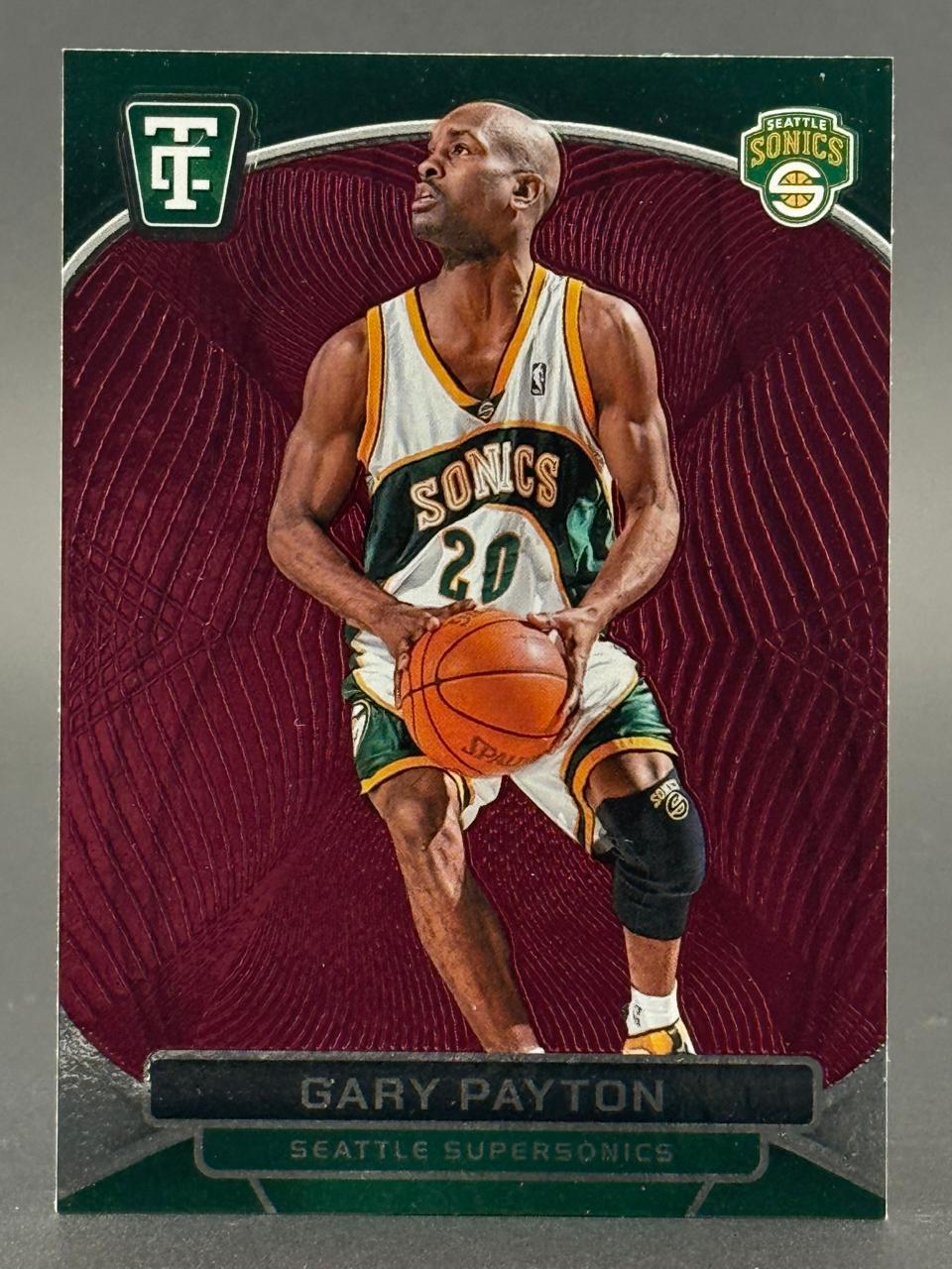 Gary Payton trading card holding a basketball in Seattle Supersonics uniform against a maroon background.