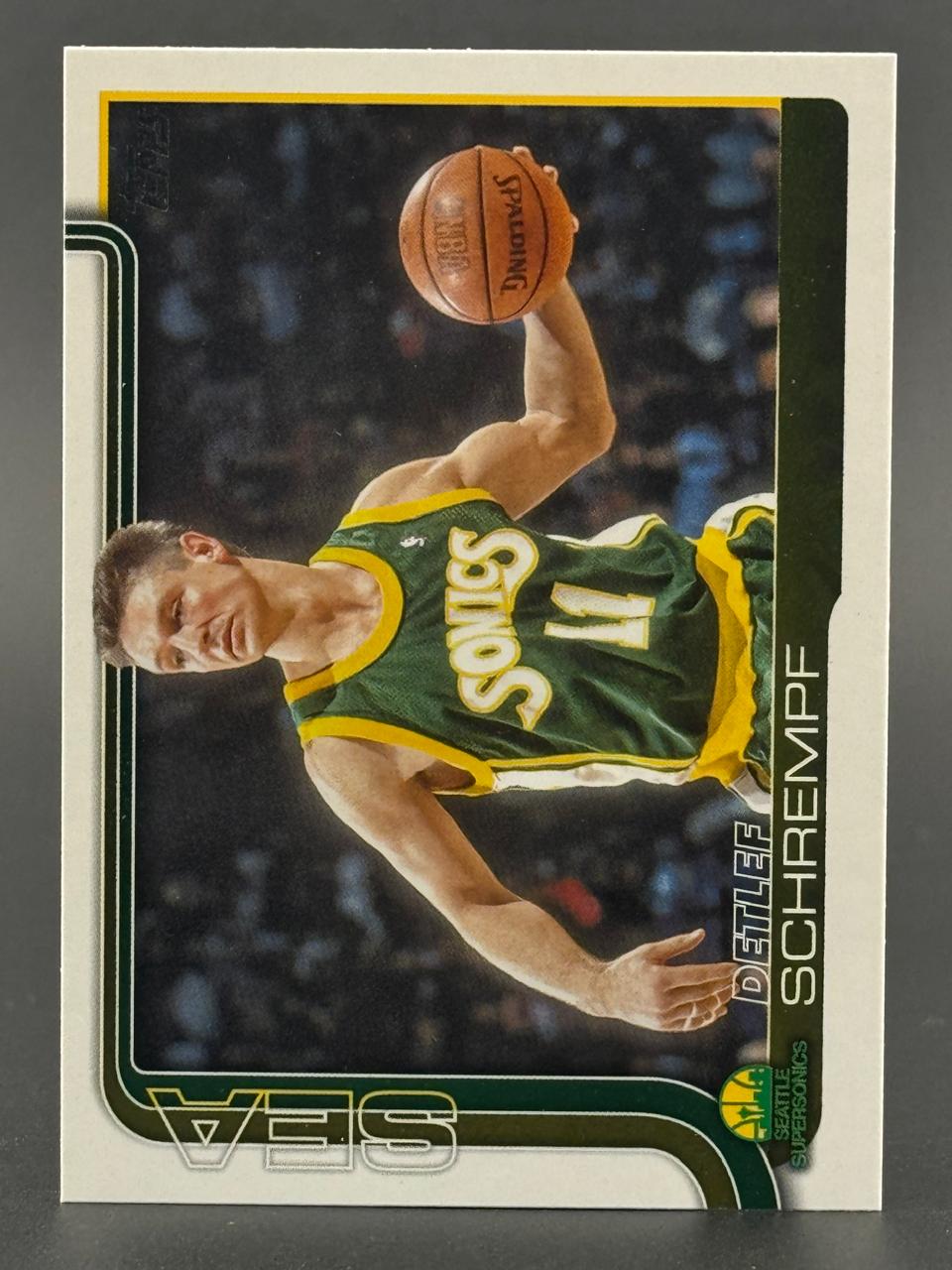 Trading card of Detlef Schrempf in a Seattle SuperSonics jersey holding a basketball above his head.