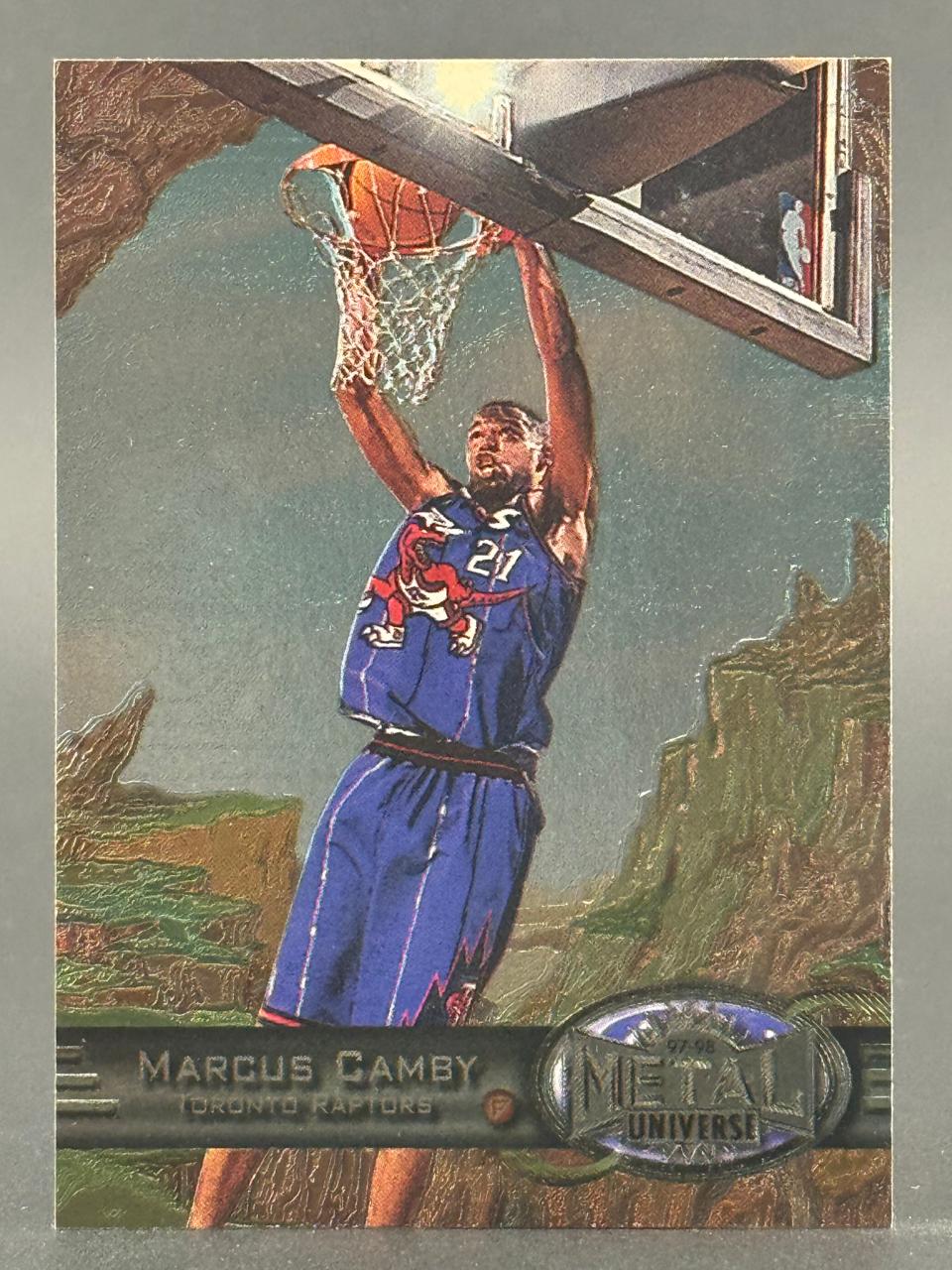 1997-98 Metal Universe Marcus Camby basketball card, showing him dunking in a Raptors uniform.