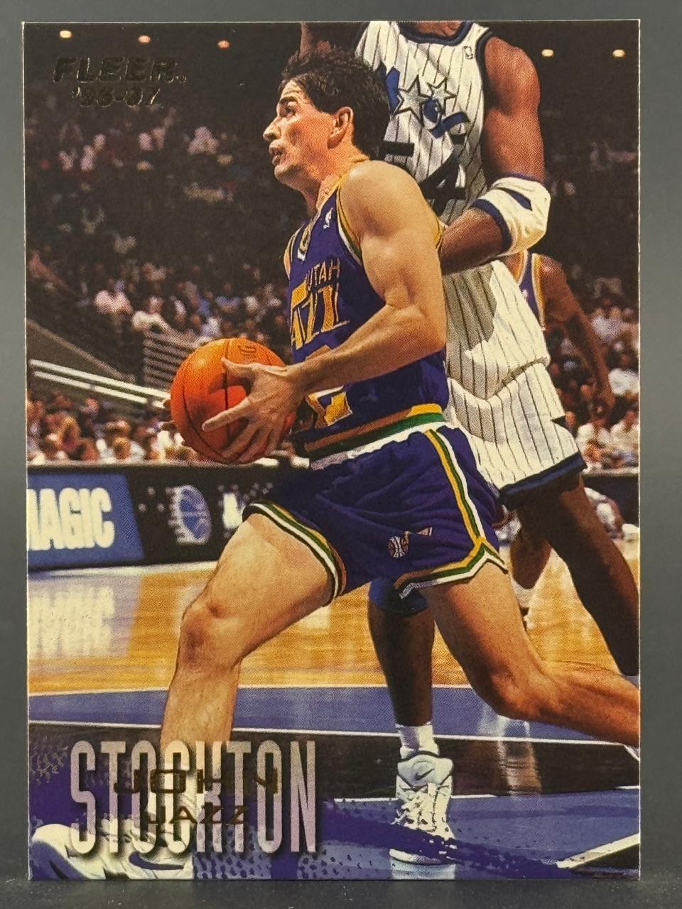1996-97 Fleer John Stockton trading card featuring him dribbling in a Utah Jazz uniform.