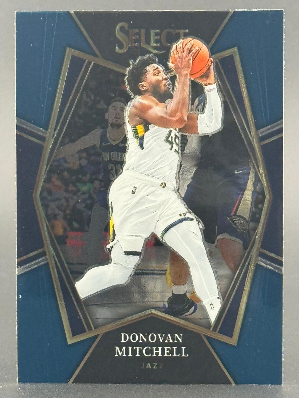Donovan Mitchell 2018-19 Panini Select basketball card holding a basketball in a Jazz uniform.