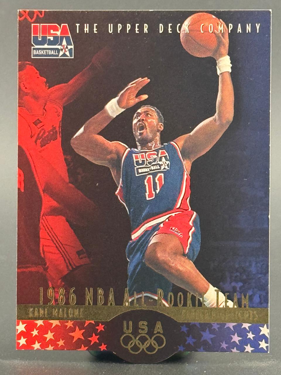 Karl Malone 1986 Upper Deck Company USA Basketball trading card showing Malone in a USA uniform holding a basketball.