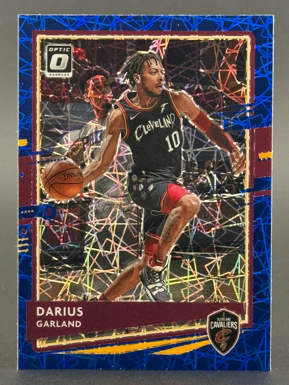 Darius Garland trading card with blue mosaic border, featuring him in a Cleveland Cavaliers uniform dribbling.
