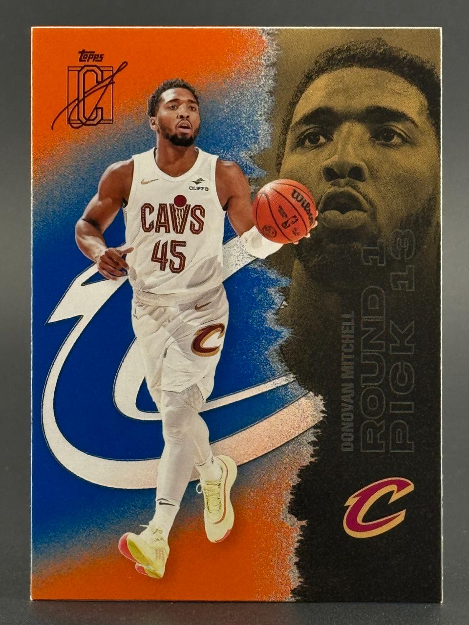 Donovan Mitchell basketball card in Cavaliers jersey with large portrait on right against orange and blue background.
