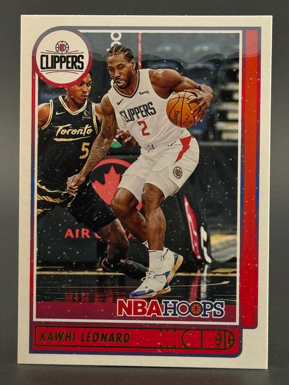Kawhi Leonard 2020-21 NBA Hoops trading card dribbling against a Toronto Raptors player.