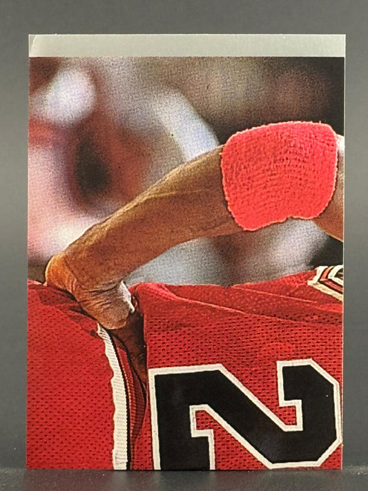 Close-up trading card showing an arm with a red wristband and a red jersey with the number 23.